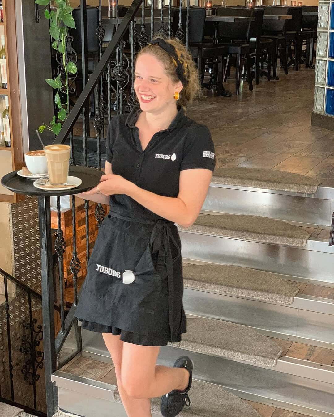 Smilende tjener serverer kaffe på bakke på Café Moccador